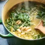Rustic spinach and white bean soup with orzo simmering in a green Dutch oven
