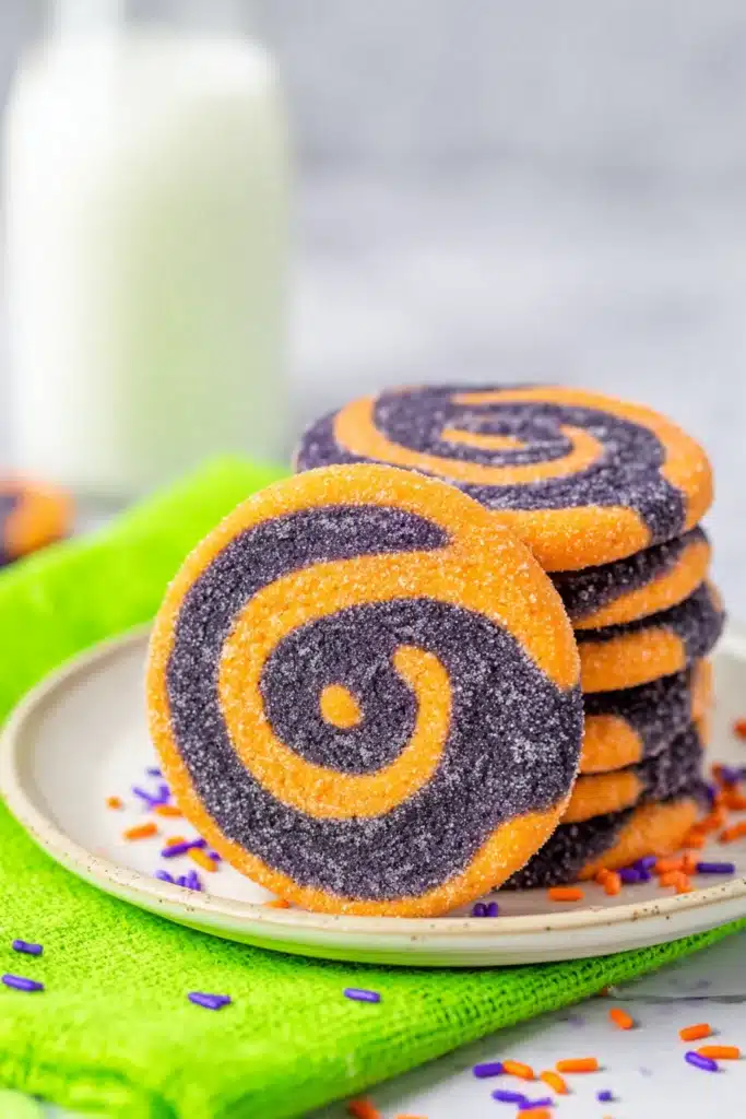 Stacked Halloween pinwheel cookies with orange and black swirls on white plate