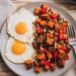 Sweet potato breakfast hash with sausage and Mickey-shaped eggs on a white plate