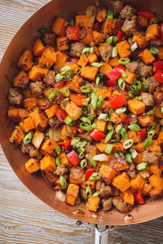 Sweet potato breakfast hash topped with scallions in skillet