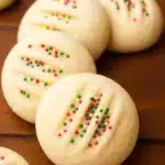 Whipped shortbread cookies with sprinkles and fork marks on a cookie tray