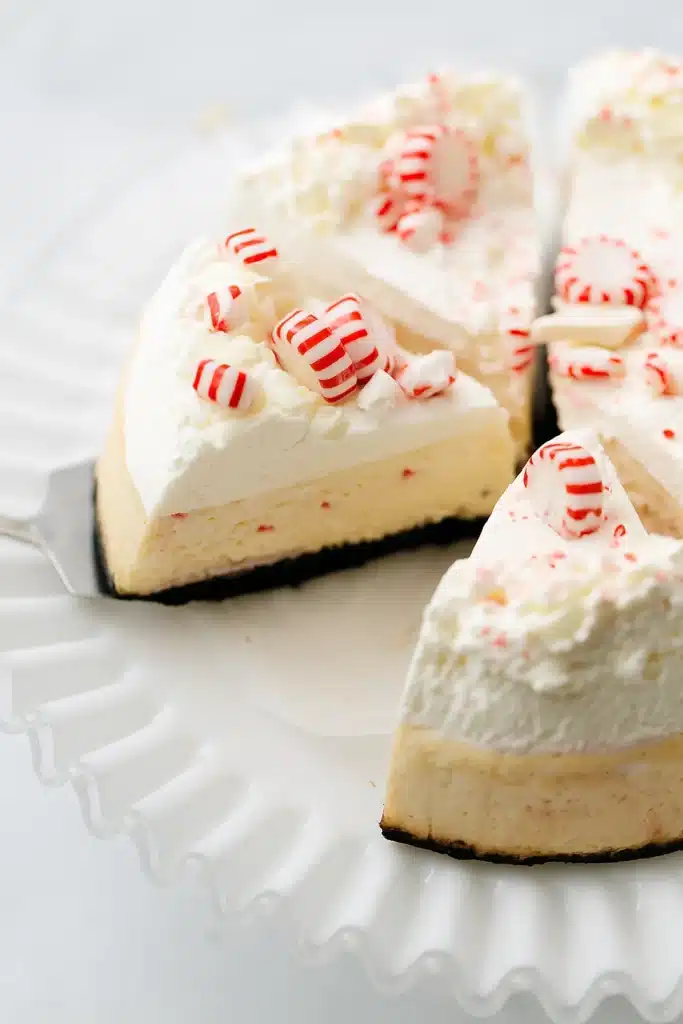 Slice of white chocolate peppermint cheesecake with whipped cream and candy canes