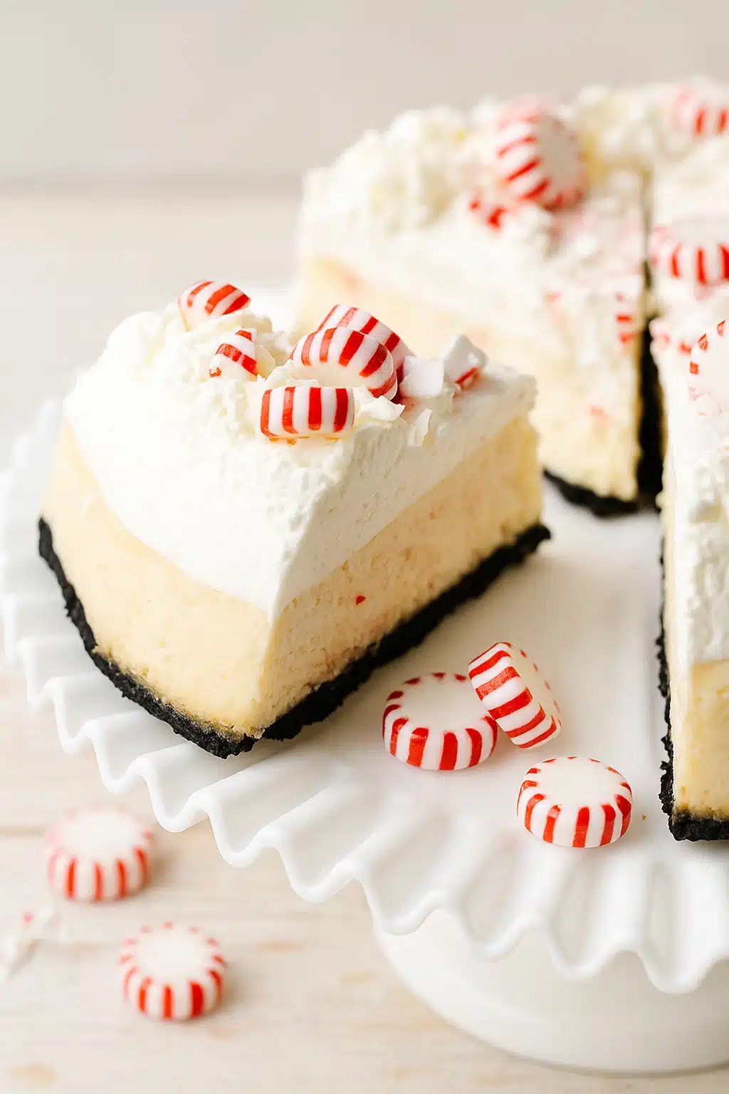 Slice of white chocolate peppermint cheesecake with whipped cream and crushed candy canes