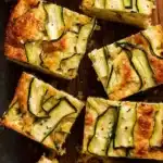 Zucchini Cheese Muffin Slab – Easy & Delicious Recipe 9 Golden zucchini cheese muffin slab slices with roasted zucchini topping on a slate surface