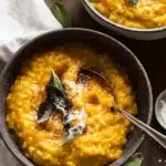 Creamy baked pumpkin risotto topped with crispy sage in a rustic bowl