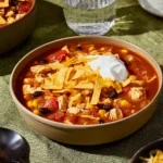 Slow Cooker Chicken Taco Soup | Easy & Delicious Meal 10 Slow Cooker Chicken Taco Soup topped with cheddar, sour cream, and tortilla chips in a ceramic bowl