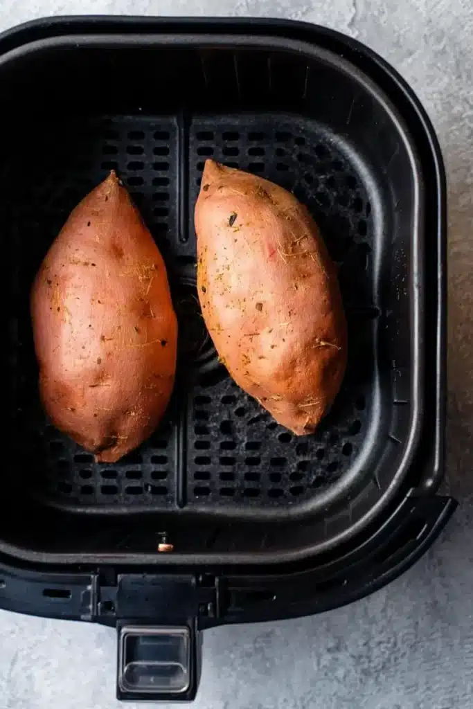 Sweet potatoes pricked and ready to cook in air fryer basket