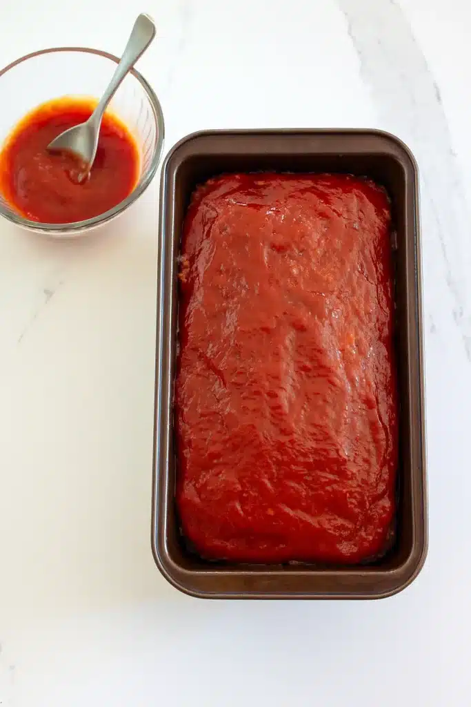 Baked vegetarian meatloaf in loaf pan with ketchup glaze bowl