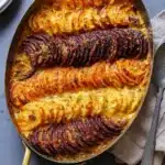 Cheesy root vegetable gratin with golden crispy layers in a rustic oval baking dish
