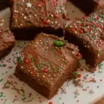 Chocolate Frosted Christmas Brownies | Amazing Holiday Treat 12 Chocolate frosted Christmas brownies with red, green, and white sprinkles on a cake stand