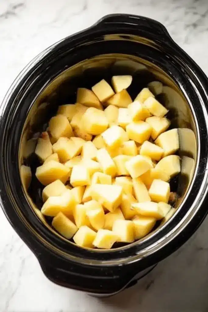 Crockpot mashed potatoes recipe with chopped Yukon Gold potatoes in slow cooker