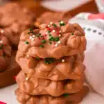 Christmas crock pot candy peanut clusters with festive sprinkles stacked on a table