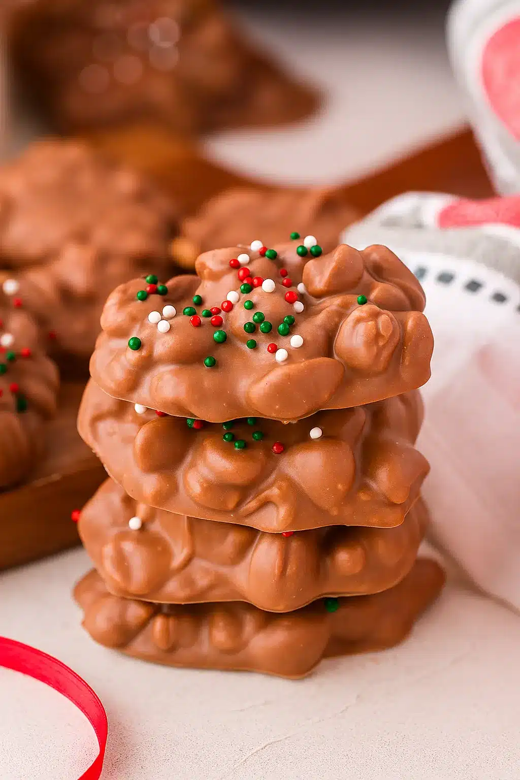Christmas crock pot candy peanut clusters with festive sprinkles stacked on a table