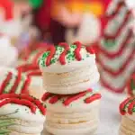 Christmas Tree Cake Macarons with red frosting drizzle and green sprinkles
