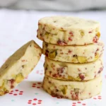 Stack of cranberry pistachio shortbread cookies on a light festive background