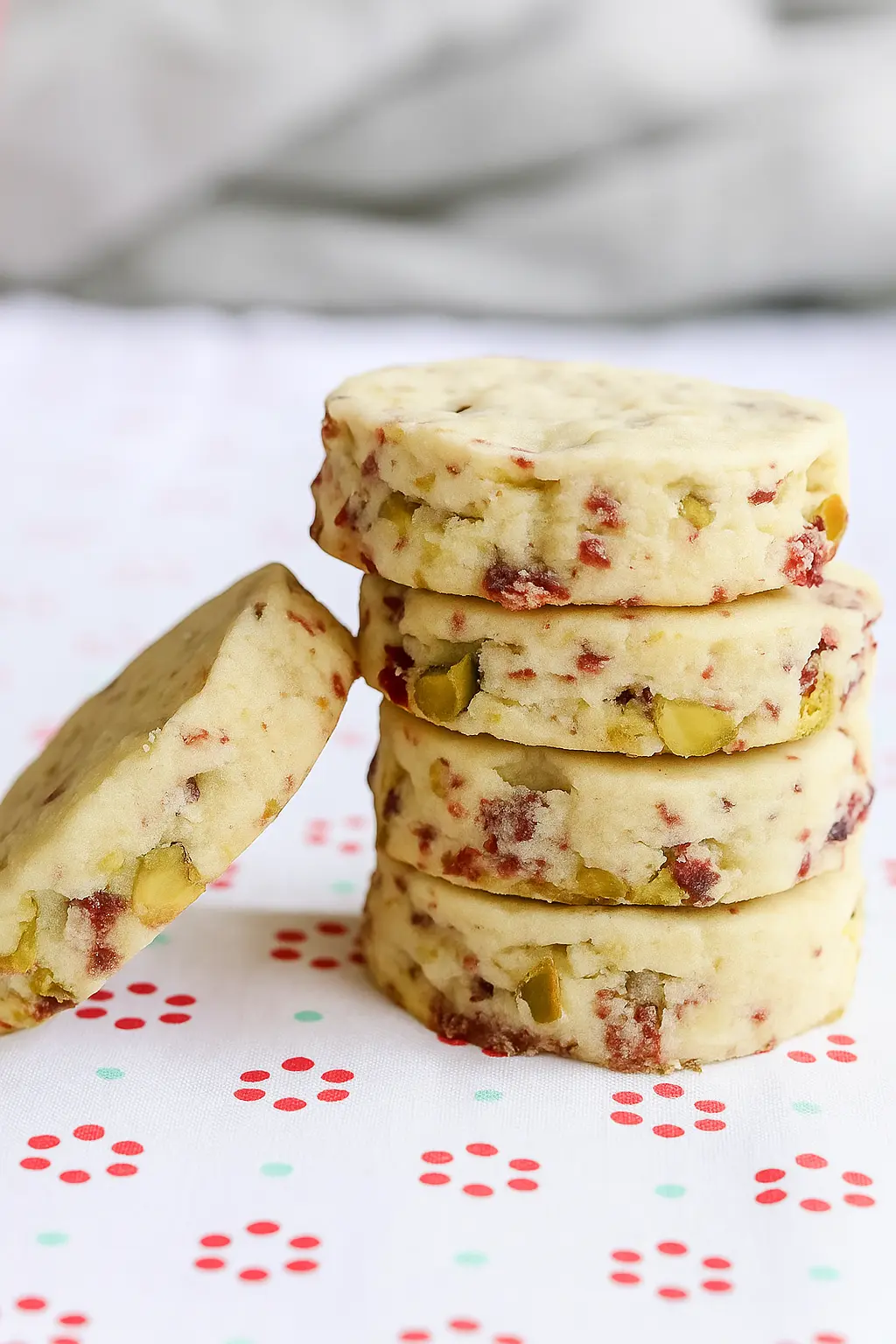 Stack of cranberry pistachio shortbread cookies on a light festive background