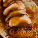 Sliced Crock Pot turkey breast with cranberry gravy on floral plate