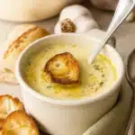 Bowl of French garlic soup with toasted bread and olive oil drizzle