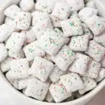 Holiday Puppy Chow Recipe | Easy, Festive & Addictive Snack 12 Close-up of Holiday Puppy Chow with powdered sugar and red-green sprinkles