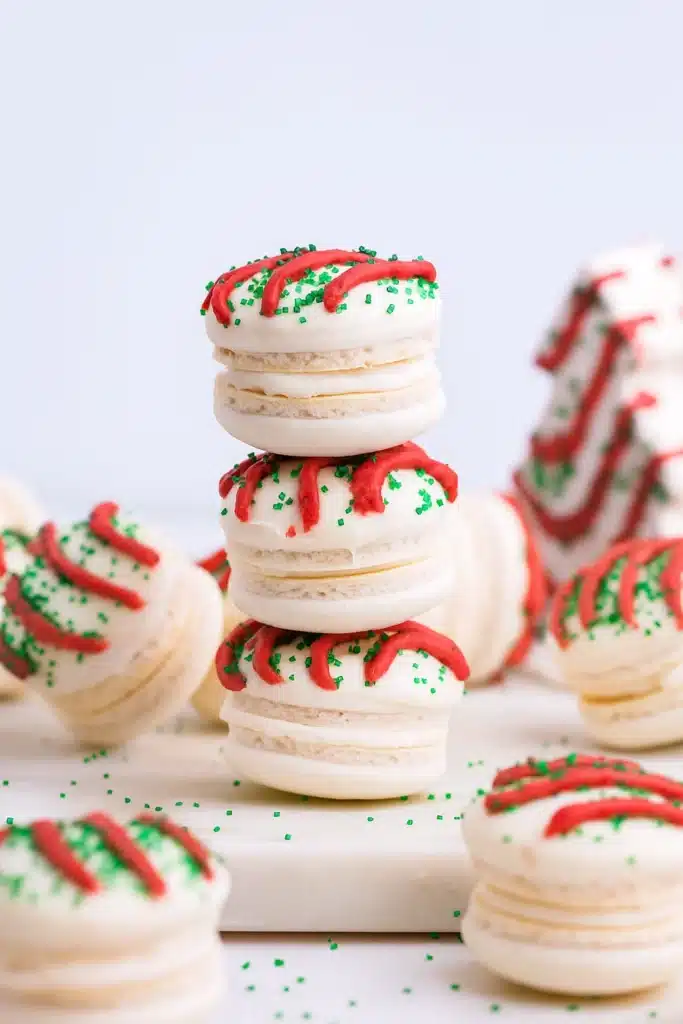 Christmas Tree Cake Macarons stacked with red drizzle and green sprinkles
