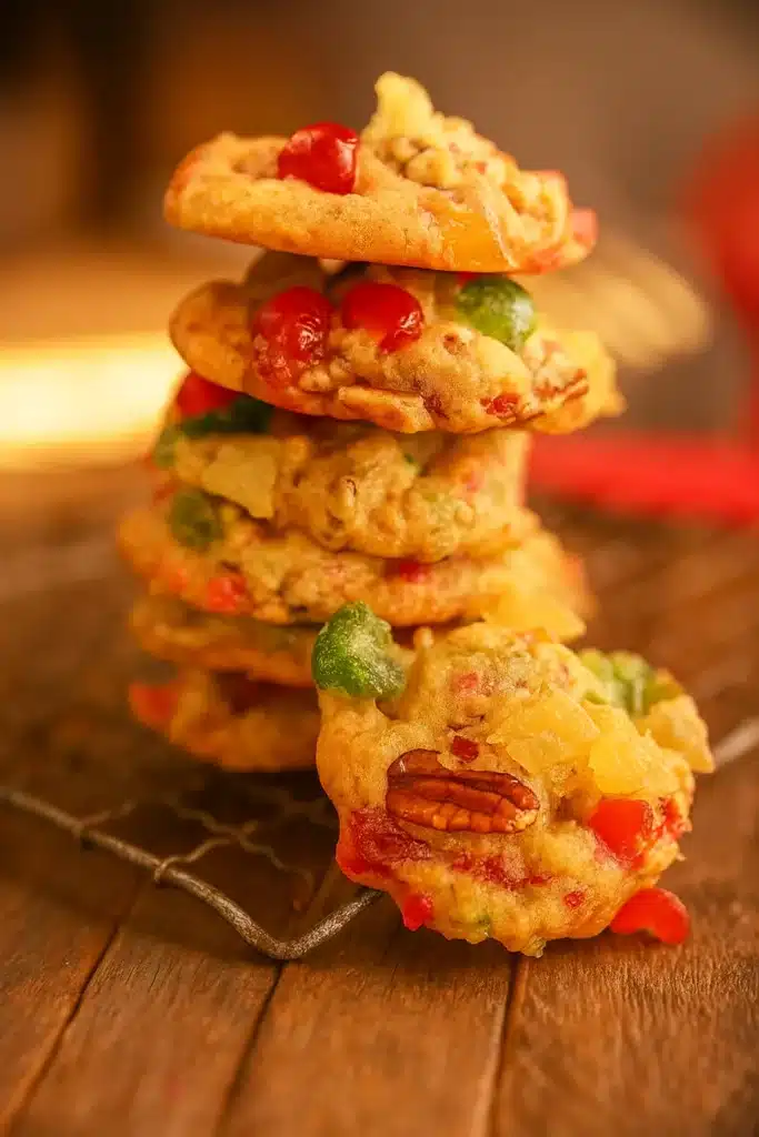 Stack of old fashioned fruitcake cookies with cherries and pecans on wooden surface