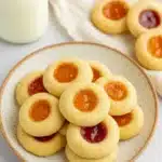 Thumbprint Cookies – Simple, Delicious, and Irresistible 12 Thumbprint cookies with jam on white plate on white-gray table