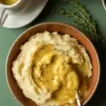 Vegan gravy over mashed potatoes in rustic bowl with thyme
