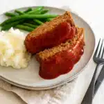Vegetarian meatloaf with mashed potatoes and green beans on a dinner plate
