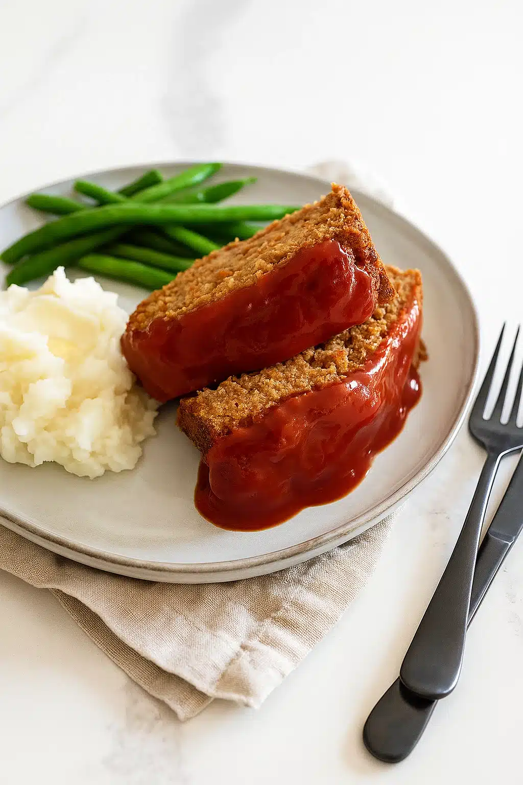 Vegetarian meatloaf with mashed potatoes and green beans on a dinner plate