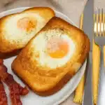 Air fryer egg toast with runny yolks and crispy bacon on a breakfast plate