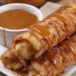 Apple pie taquitos drizzled with caramel sauce on white plate
