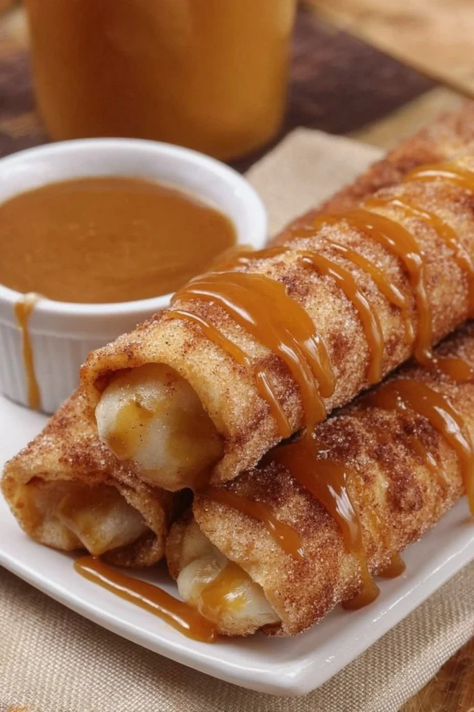 Apple pie taquitos drizzled with caramel sauce on white plate