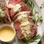 Sliced beef fillet with Bearnaise sauce and tarragon on white plate