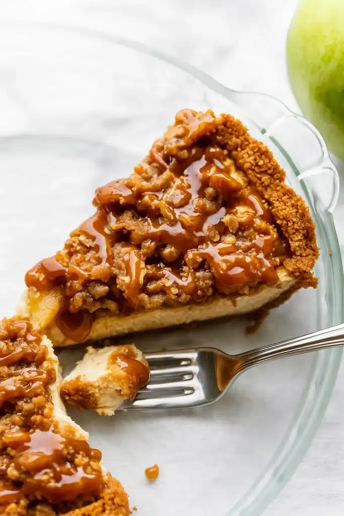 Slice of caramel apple cheesecake with caramel drizzle and crunchy streusel topping