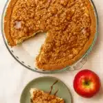 Caramel apple cheesecake with streusel topping and caramel drizzle on green plate