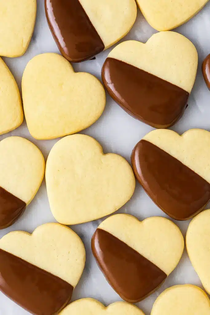 Shortbread Cookie Recipe | Simple & Delicious Holiday Treat 12 Heart-shaped shortbread cookies dipped in dark chocolate on marble surface