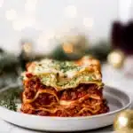 Festive Christmas Eve lasagna slice with layers of red bolognese and green pesto ricotta