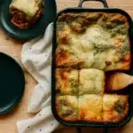Festive Christmas lasagna with golden cheese and spinach layers in a baking dish