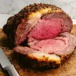 Juicy Christmas prime rib with garlic herb crust sliced on wooden board
