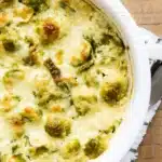 Creamy Brussels Sprouts Bake with golden melted cheese in white casserole dish