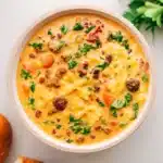 Creamy sausage pasta soup with kale and sun-dried tomatoes in a rustic bowl