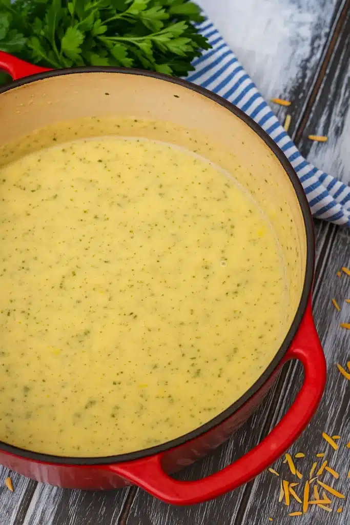 Creamy zucchini soup in red Dutch oven on rustic wooden table