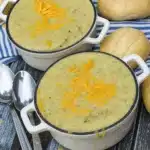 Creamy zucchini soup topped with cheddar cheese in white bowls
