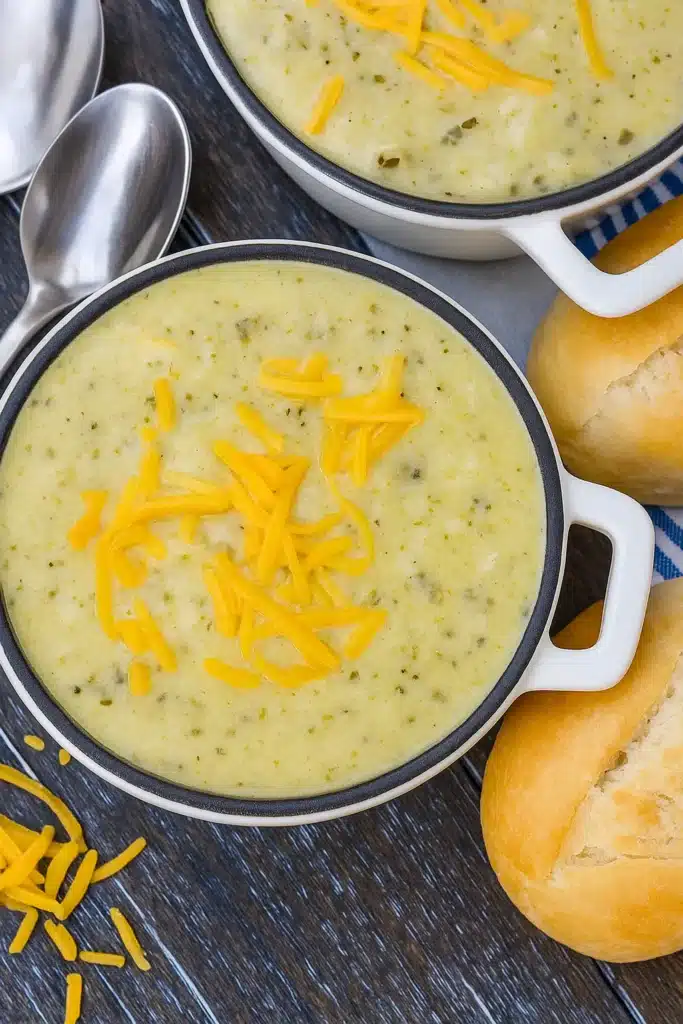 Creamy zucchini soup topped with cheddar cheese and served with bread rolls