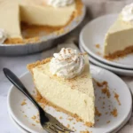 Creamy no-bake eggnog pie slice with whipped cream and nutmeg on a white plate