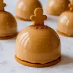 Glossy gingerbread latte mousse domes on cookie bases topped with mini gingerbread cookies