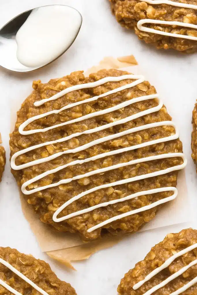 Gingerbread Oatmeal Cookies: Amazing Soft Holiday Treats 9 Soft gingerbread oatmeal cookie drizzled with white icing on parchment paper