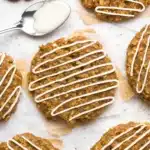 Gingerbread oatmeal cookies with white icing drizzles on parchment paper