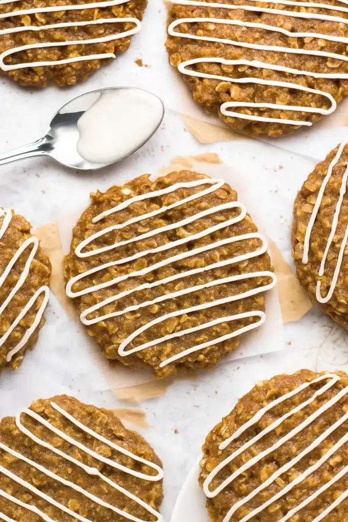 Gingerbread oatmeal cookies with white icing drizzles on parchment paper