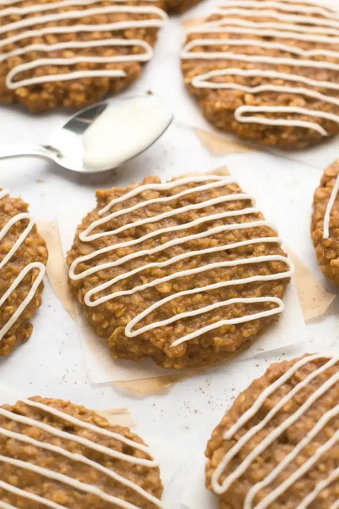 Gingerbread Oatmeal Cookies: Amazing Soft Holiday Treats 12 Soft gingerbread oatmeal cookies drizzled with white icing on parchment paper